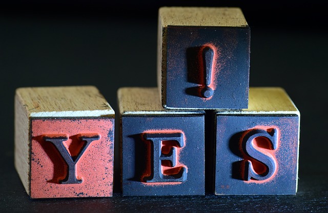 The word yes written on a cube stamp - indicating a "yes-man" real estate agent