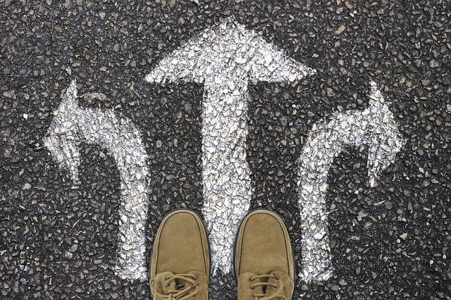 Feet at a crossroad with three option painted on the road surface