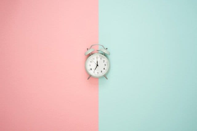 A small alarm clock on a pink and blue background